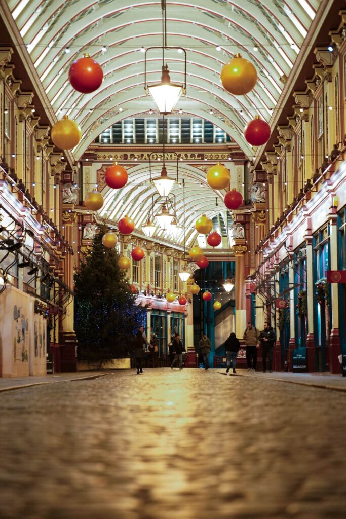 Leadenhall Market decorated for Christmas in London, with red and gold baubles hanging along the painted arcade.