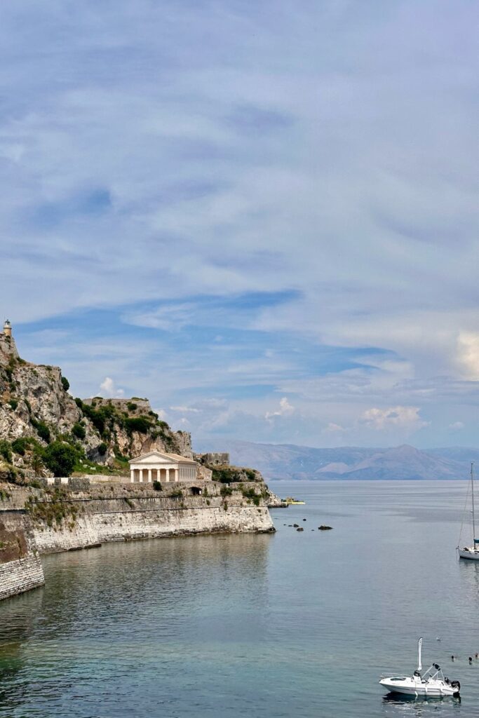 The neoclassical Church of St. George below the Old Fortress in Corfu Town, Greece, with calm sea and mountains in the distance