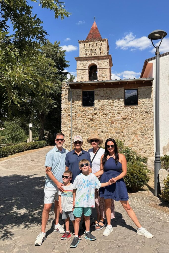 Family in front of a stone church bell tower in a small Italian village