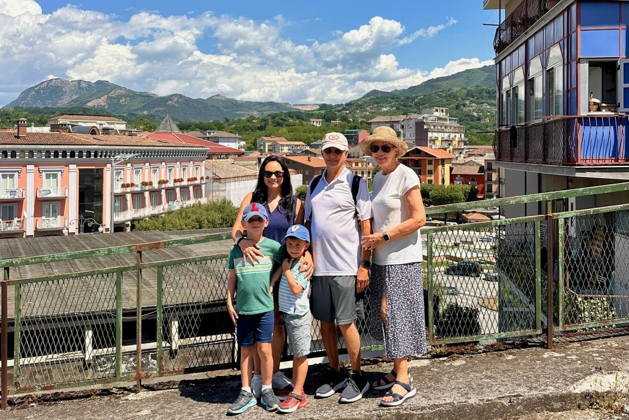Mari, her sons and her parents at an overlook above a small southern Italian town with green mountains behind