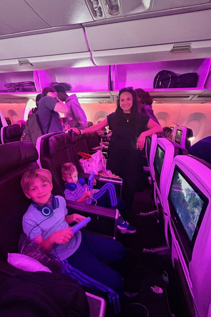 Mari standing in the aisle while her boys watch tablets in their seats under purple cabin lighting